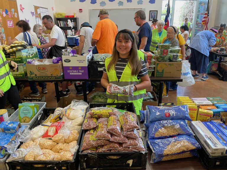 smiling girl holding bag of beans at table full of dry goods