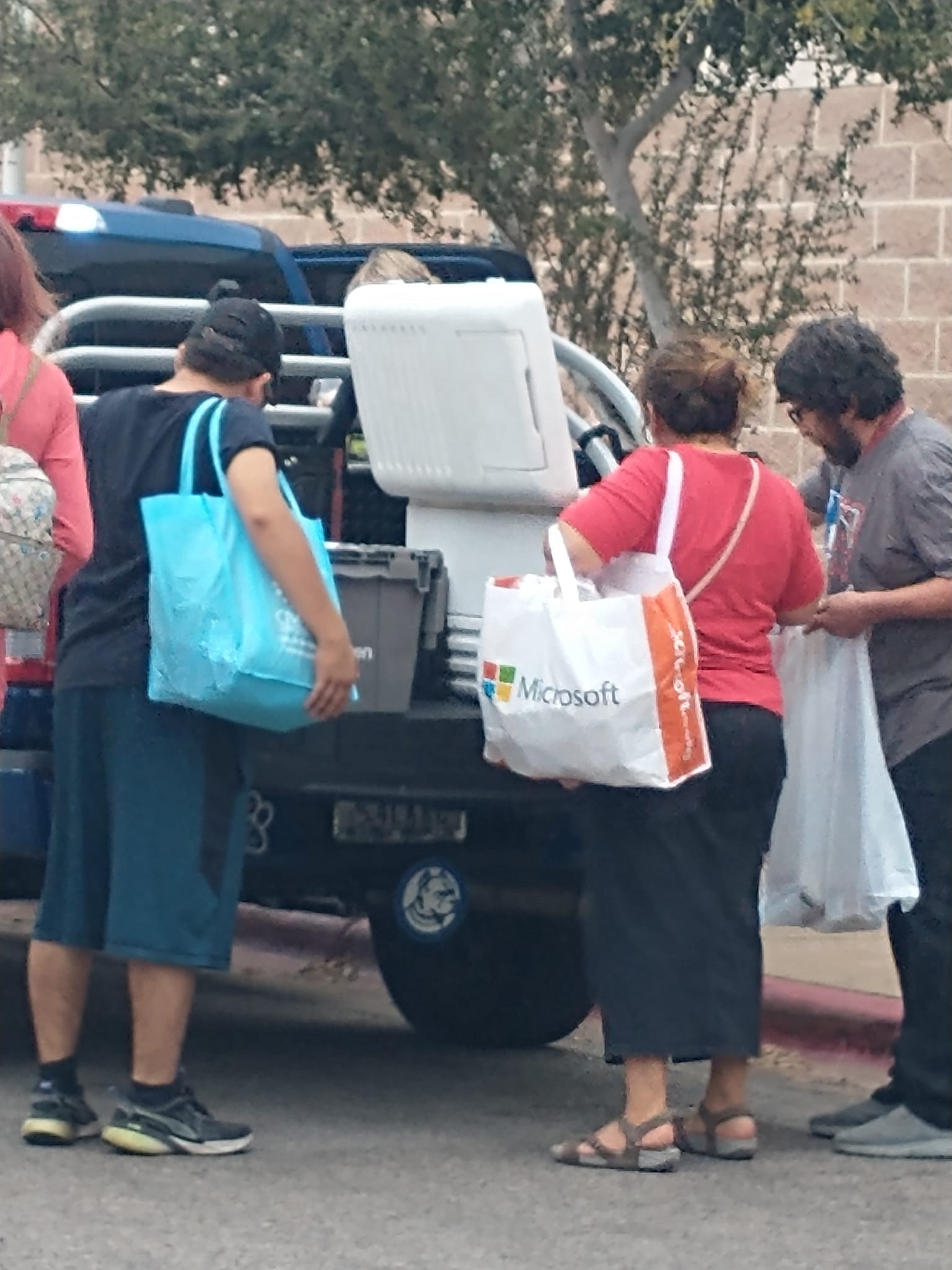 people in bright colored shirts getting food from cooler