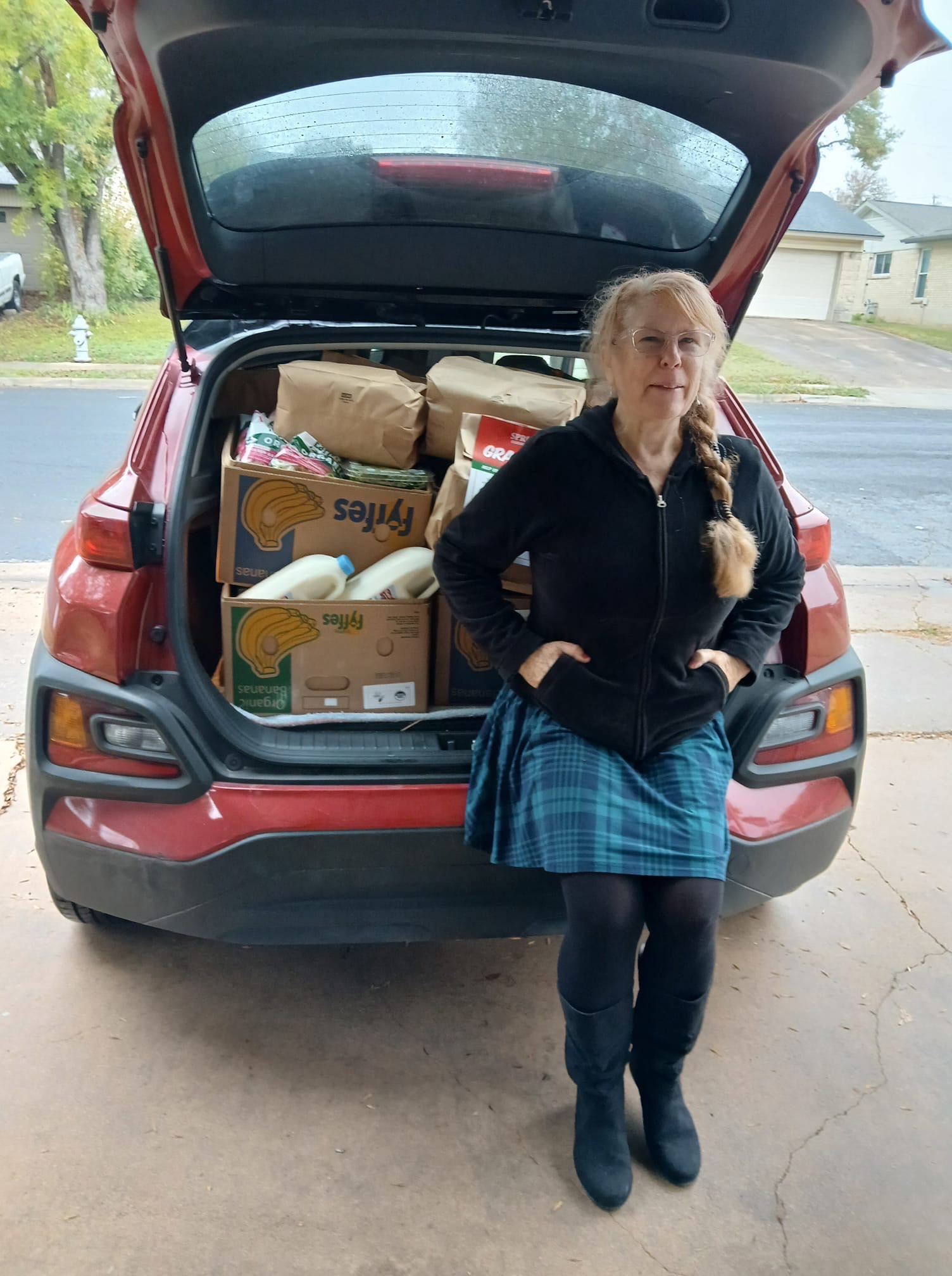 woman standing by a red car with boxes of food in the bed