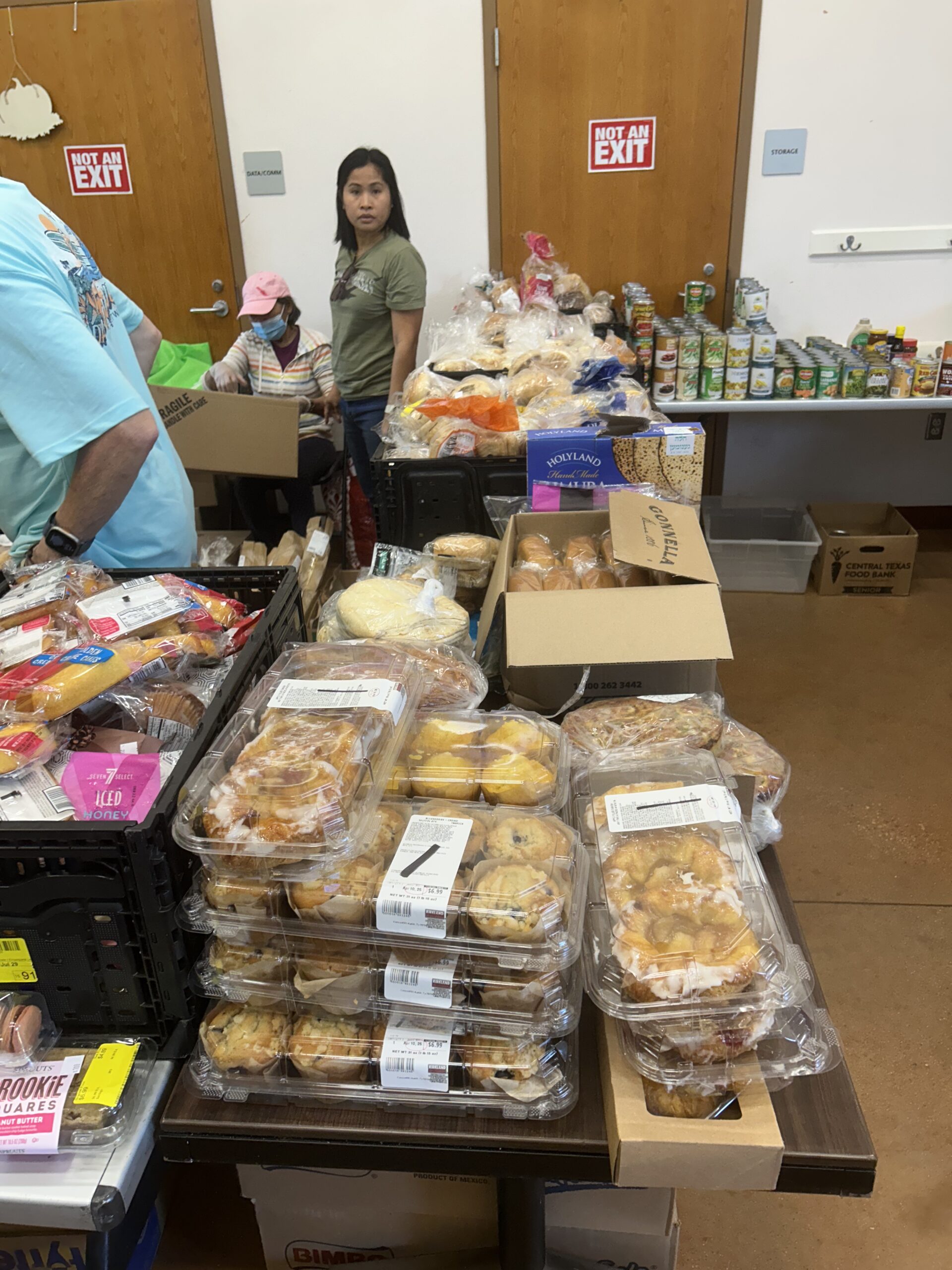 table of bread items with 2 volunteers working to stock the table