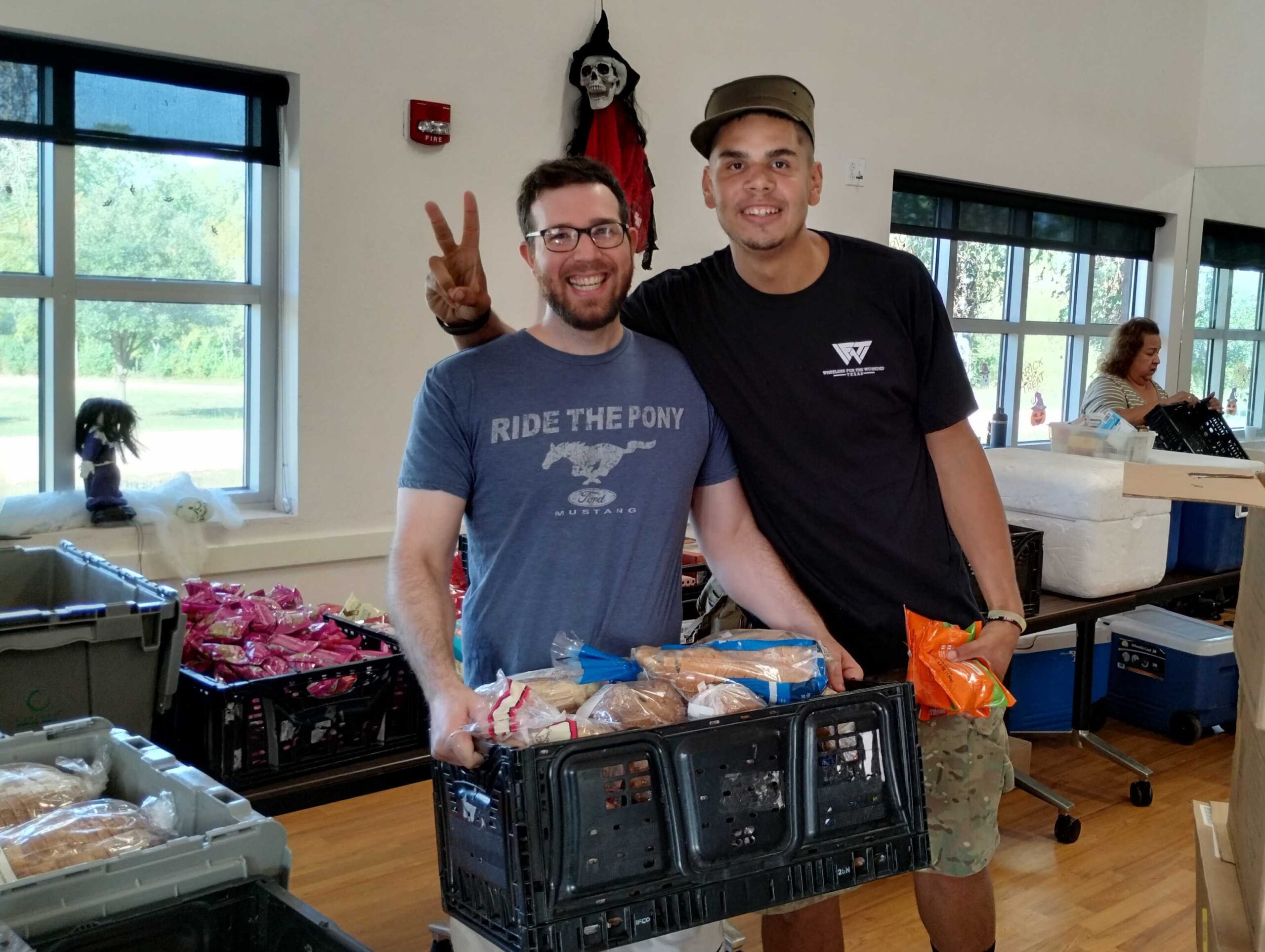 2 men with a crate of food fooling around at the pantry