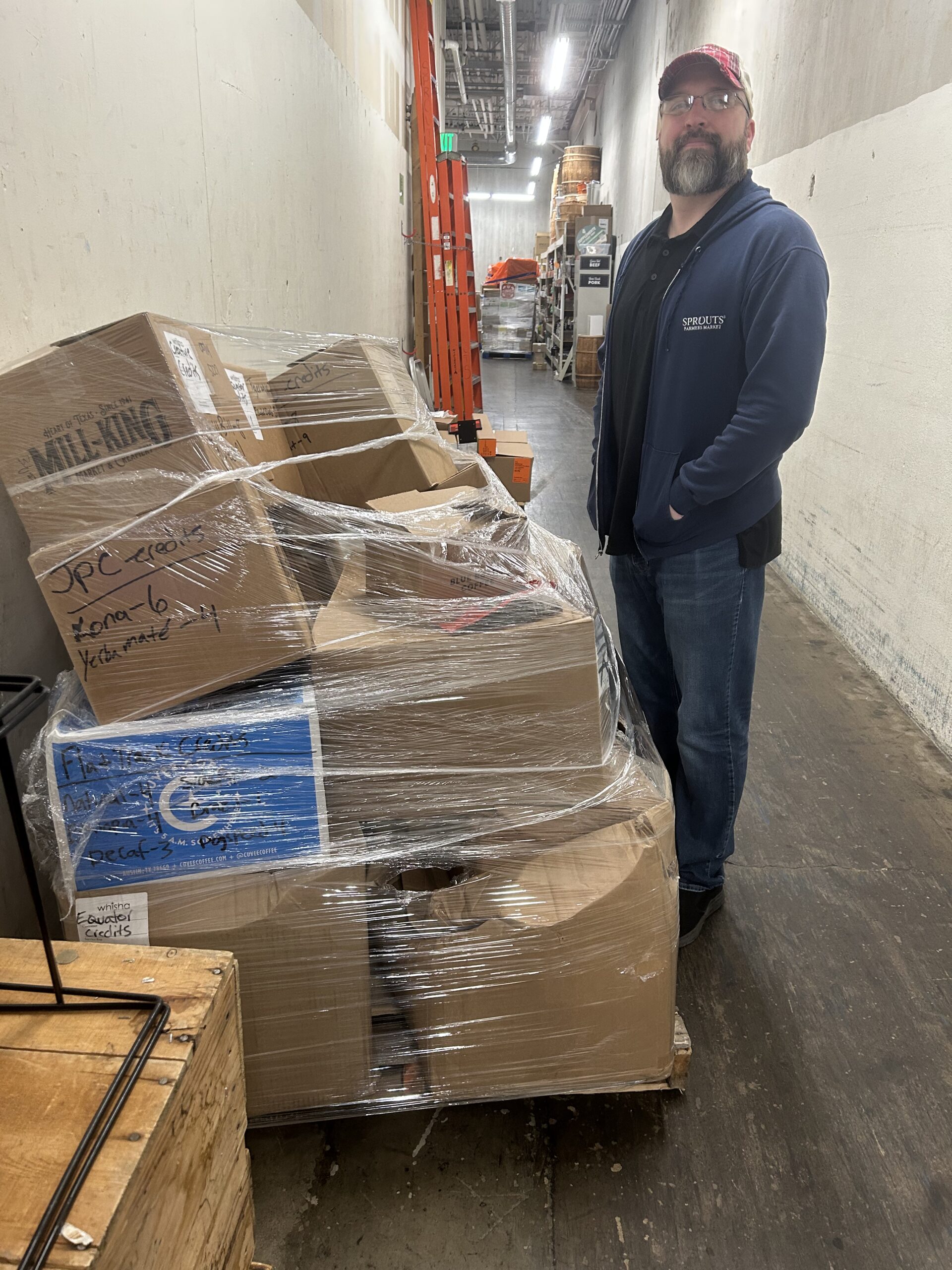 man standing next to pallet of boxes of coffee