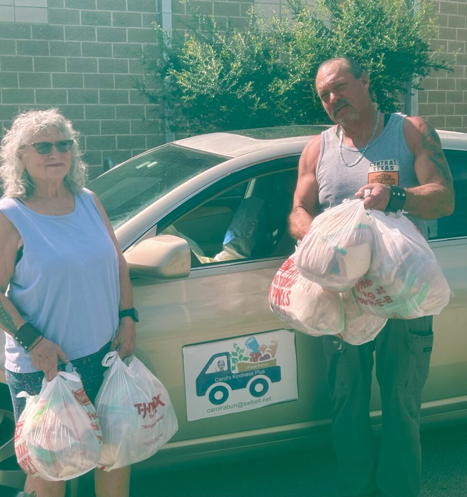 91E2167A-ABAF-41B8-B555-9C9149FCB520_1_201_a Debb and Jeff with bags of food by Car with sign Carol's Kindness on side